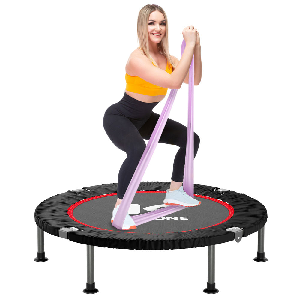 A person exercising on a 40-inch mini trampoline with a pink and black color scheme. The trampoline has a steel frame, adjustable handles, and a black mat.