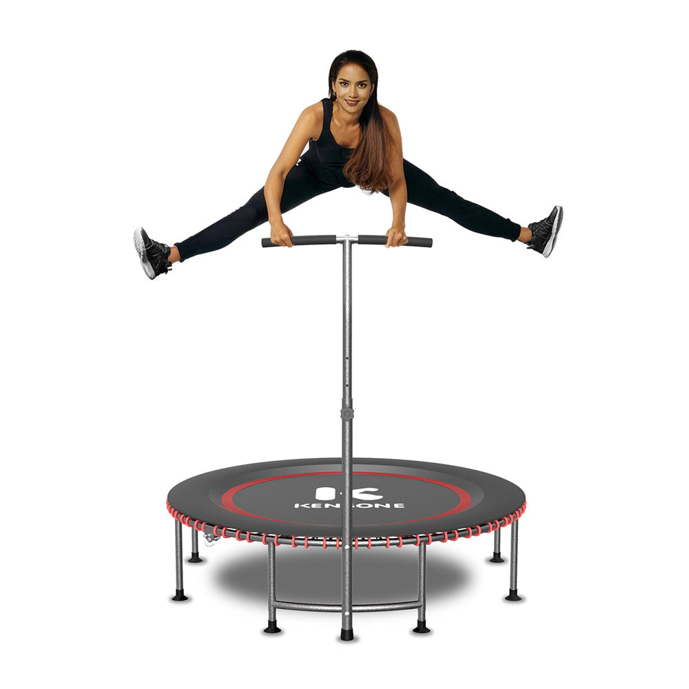 A woman exercising on a black trampoline with red markings, which has a safety bar and is placed against a white background.
