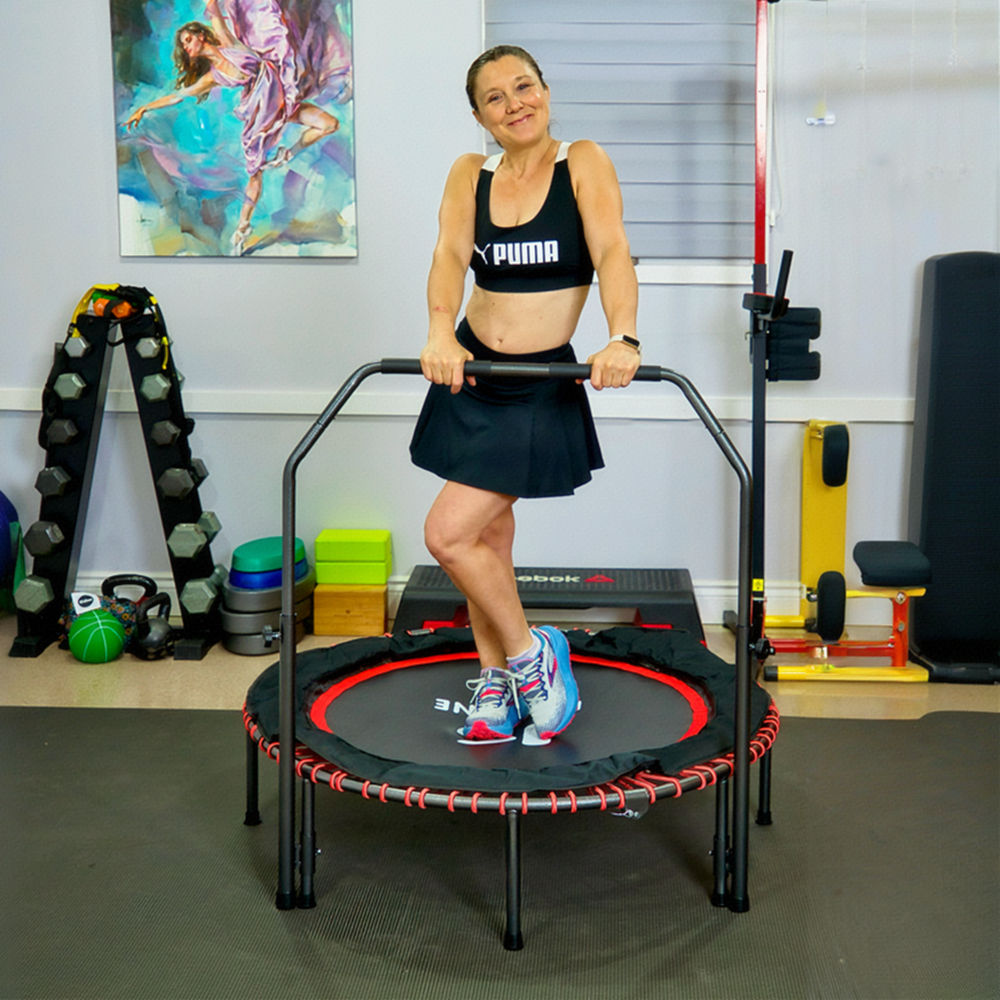 Adult woman exercising on Kensone 48-inch bungee fitness trampoline with adjustable U-bar handlebar in a home gym setting.