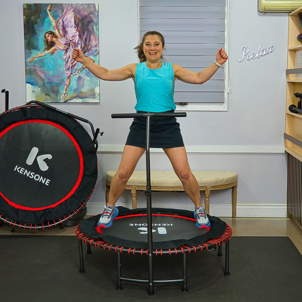 Adult woman exercising on Kensone 48-inch bungee fitness trampoline with adjustable T-bar handlebar in a home gym setting.