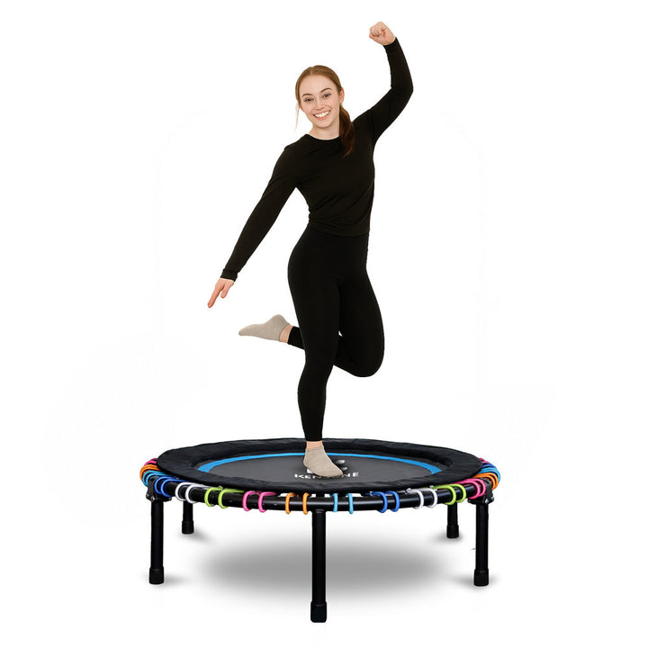 Woman jumping on a small trampoline with colorful bungees a white background