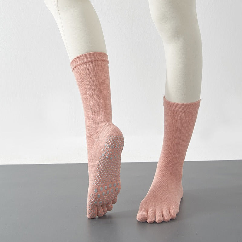Pink socks with textured sole worn by a person on a gray surface with a white background