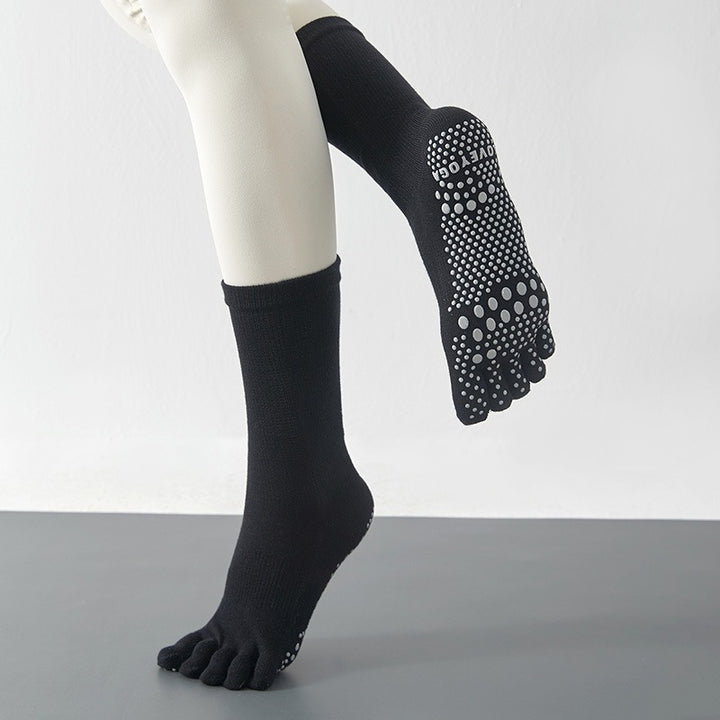 Black socks with grip dots worn on a mannequin against a plain background