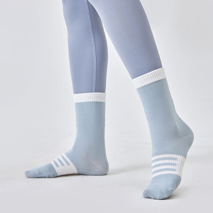 Light blue socks with white stripes worn with light blue leggings on a plain background