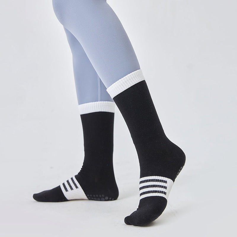 Black socks with white stripes worn by a person on a light gray background