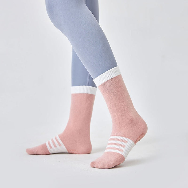 Person wearing light blue leggings and pink socks with white stripes on a plain background