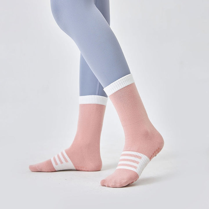 Person wearing light blue leggings and pink socks with white stripes on a plain background