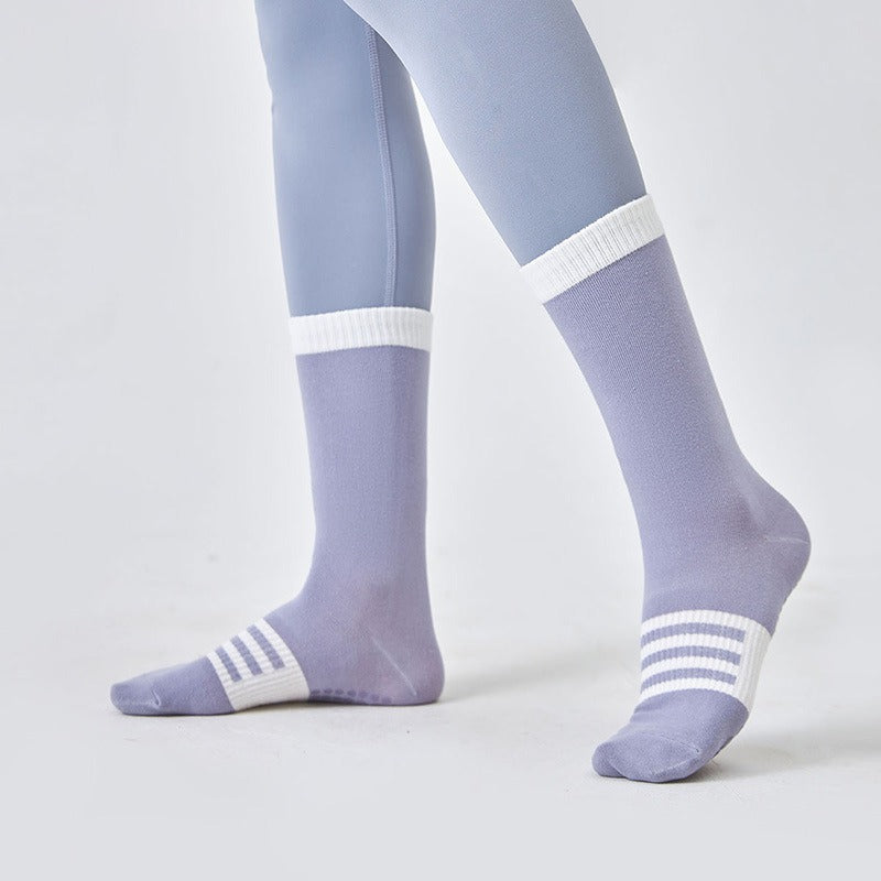 Purple socks with white stripes worn with light blue tights on a plain background