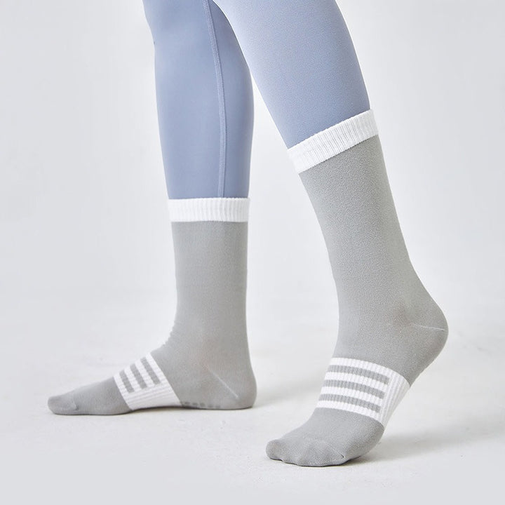 Gray socks with white stripes worn by a person on a light gray background